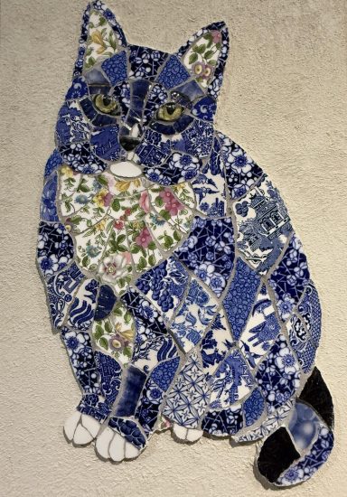 A decorative patchwork cat made from blue and floral patterned fabric.