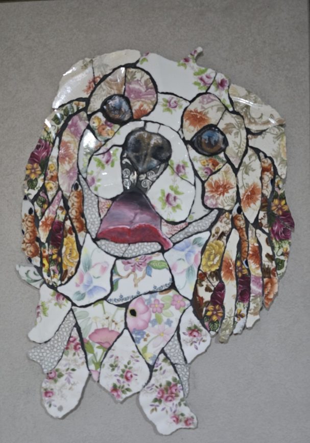 “Handmade mosaic portrait of a Cavalier King Charles Spaniel created from hand‑cut vintage china plates in warm natural tones.”