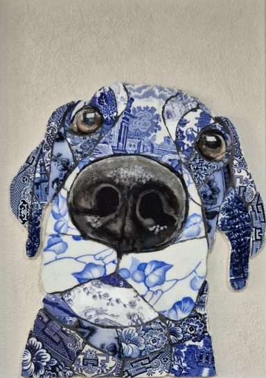 Close-up mosaic portrait of a black Labrador, highlighting its large nose and soulful eyes. Crafted from vintage china