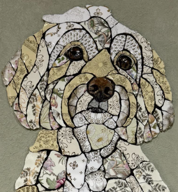 Handmade mosaic portrait of a Cavapoo created from individually hand‑cut vintage china plates in soft cream and patterned tones.”