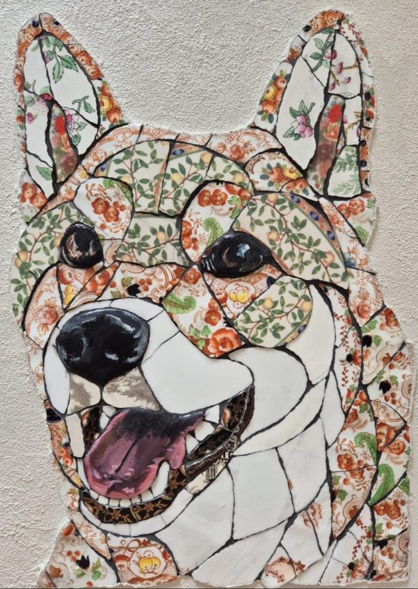 Handmade mosaic portrait of a Japanese Akita created from individually hand‑cut vintage china plates in dark and neutral tones.”